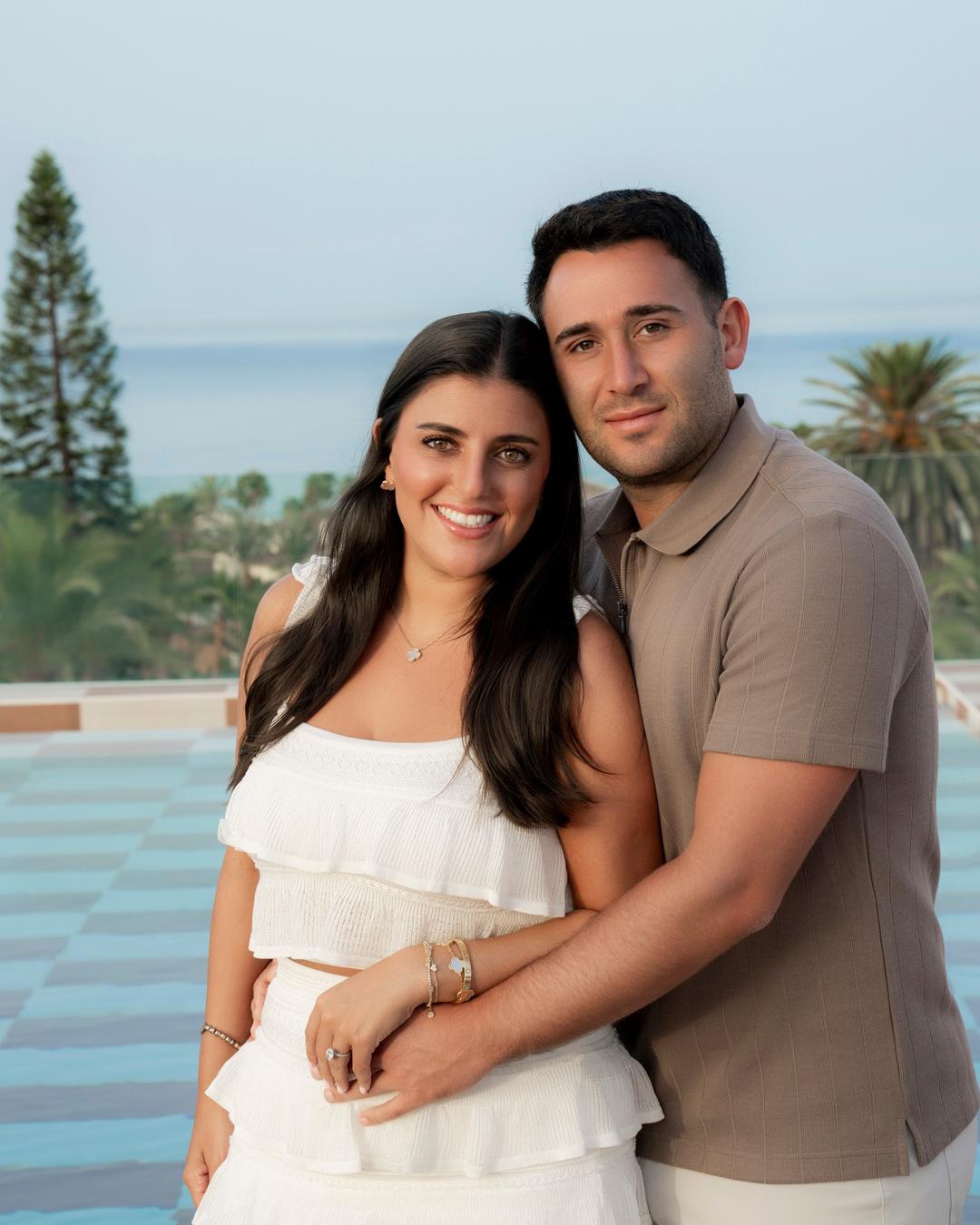 Engagement portrait of a smiling couple on a terrace by the sea