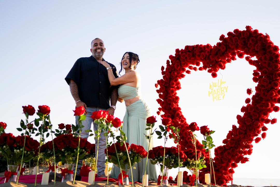Couple laughing and hugging right after the proposal, the rose heart beside them